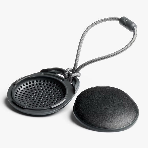 Black mesh screen and round black object with a string on a white background