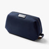 Navy blue toiletry bag with a brand logo on a light gray background