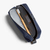 Navy toiletry bag with a toothbrush inside on a light gray background