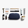 Collection of grooming products including a navy blue toiletry bag on a white background