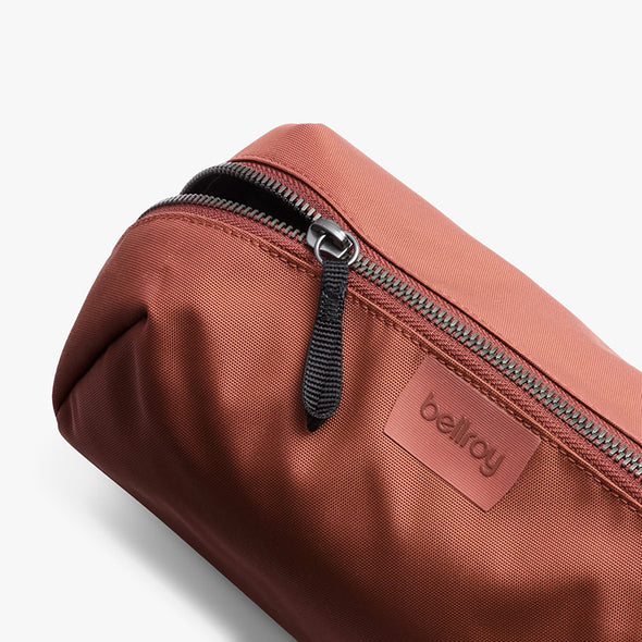 Brown toiletry bag with a zipper and visible brand logo on a white background