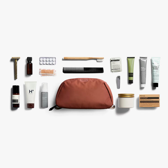 Collection of grooming products including a brown toiletry bag on a white background