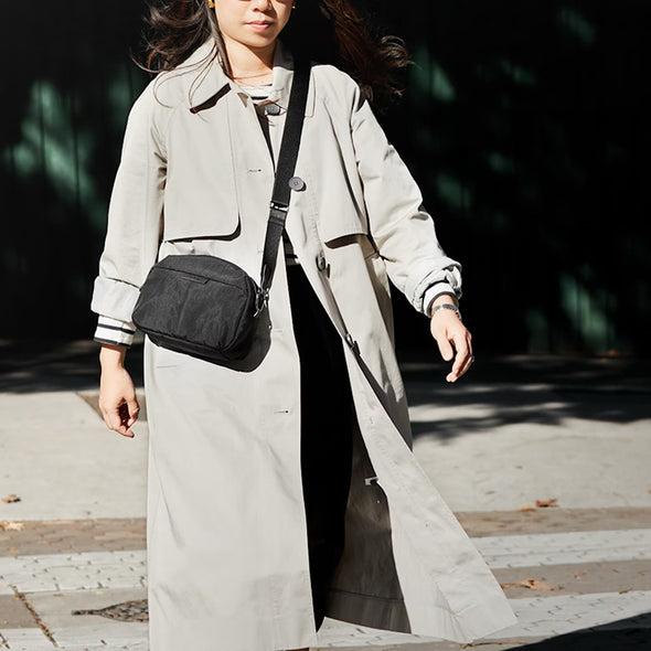 Person wearing a long coat with a black bag outdoors