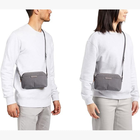 Two people wearing white sweaters with gray crossbody bags on a white background