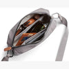 Gray crossbody bag with items inside on a white background