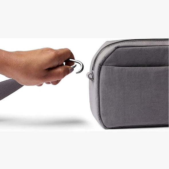 Hand zipping a gray travel bag on a white background