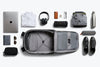 Collection of travel items arranged around an open suitcase on a white background