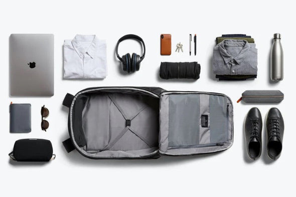 Collection of travel items arranged around an open suitcase on a white background
