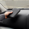 Person holding a black zippered pouch on a car dashboard