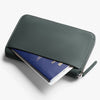 Green wallet with a passport inside on a white background