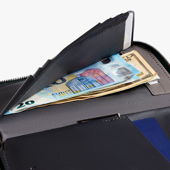 Black wallet with money, including Euro and US dollar bills, on a white background