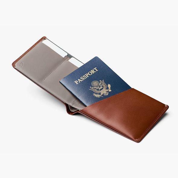 Brown leather passport holder with a blue passport inside on a white background