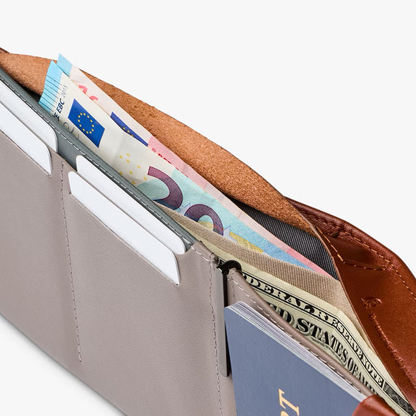 Close-up of a wallet with money and a passport inside, on a white background