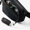 Black waist bag with a keychain attached on a white background