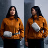 Woman wearing an orange raincoat with a white bag on a snowy background