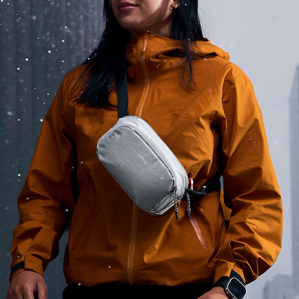 Person wearing a brown jacket with a gray crossbody bag in a snowy setting