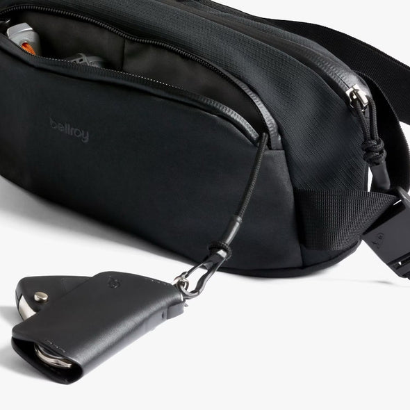 Black waist bag with a keychain attached on a white background