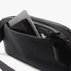 Black crossbody bag with a phone and wallet inside on a white background