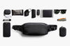 Black waist bag with various items arranged around it on a white background