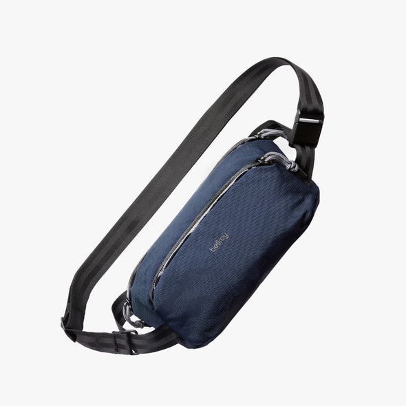 Blue sling bag with black strap on a white background