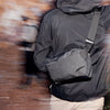 Person wearing a dark gray crossbody bag with a blurred background