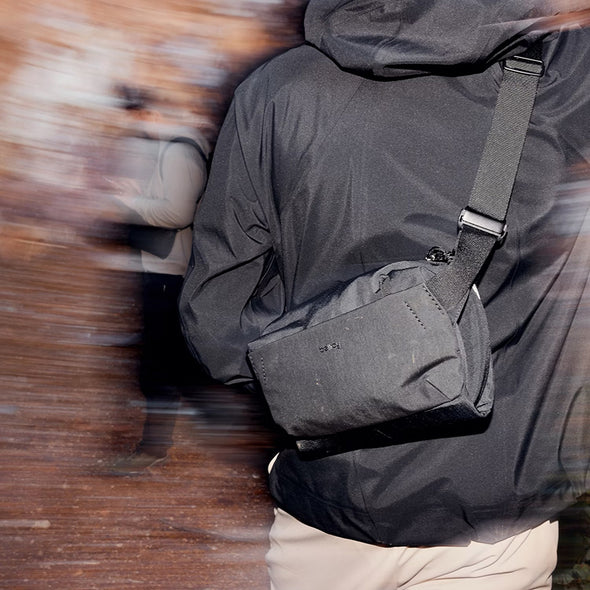 Person wearing a dark gray crossbody bag with a blurred background