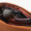 Black sunglasses inside an open brown leather bag