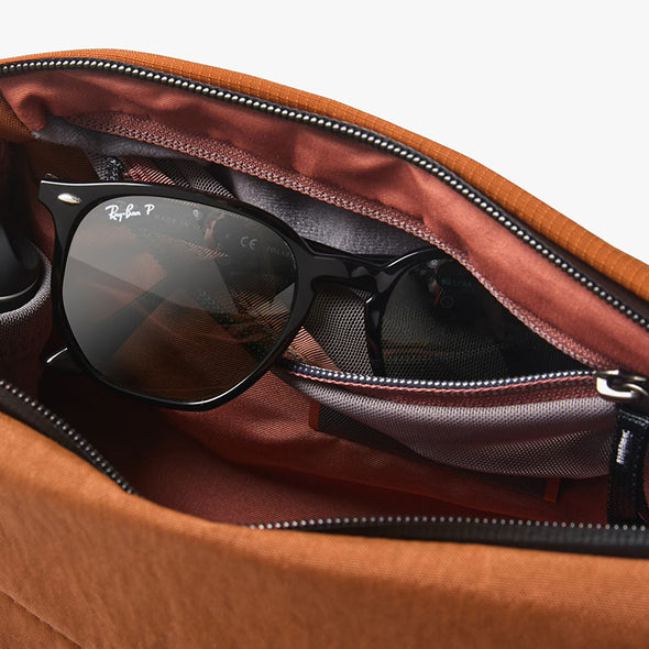 Black sunglasses inside an open brown leather bag