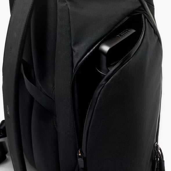 Close-up of a black backpack with a shoulder strap and zipper details on a white background