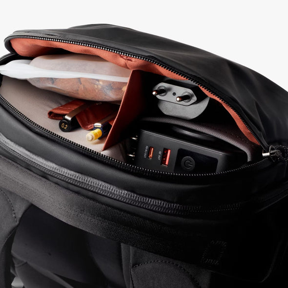 Black backpack with open compartment showing electronic devices and items.