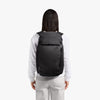 Person wearing a black backpack on a white background