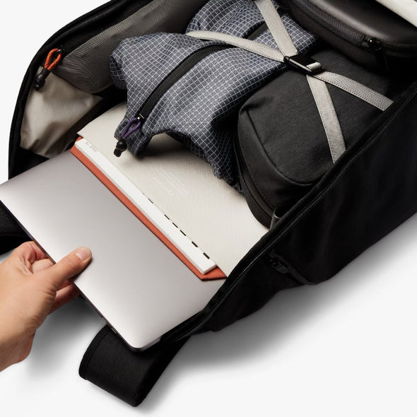 Laptop being placed into a black backpack with a white background