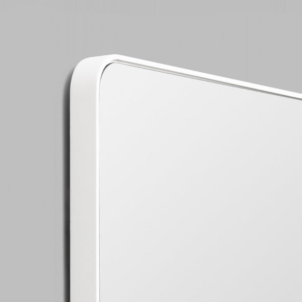 Close-up of a frame corner of the white Flynn Curve Mirror on a grey background