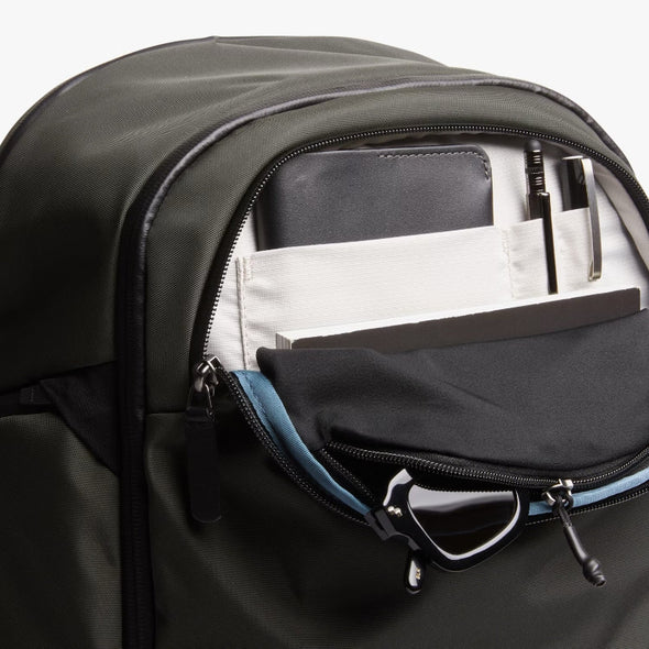 Open Bellroy Transit Workpack Pro 28L Olive backpack with compartments and items inside on a white background