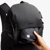 Black backpack with 'bellroy' branding held by a hand on a white background