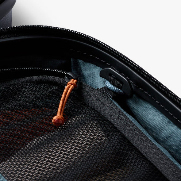 Close-up of a black bag with orange zipper pull and blue interior.