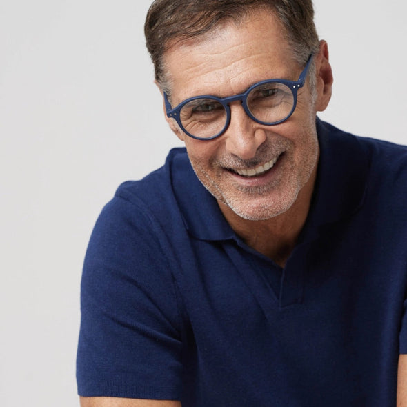 Man wearing a navy blue polo shirt and IZIPIZI Reading Glasses Collection #D Navy on a light grey background