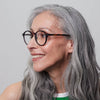 Woman with grey hair and IZIPIZI Reading Glasses Collection #D in Tortoise is smiling against a plain background