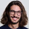 Man with long hair and IZIPIZI Reading Glasses Collection #D in black is smiling against a plain background