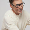 Man wearing a cream sweater and glasses against a light gray background