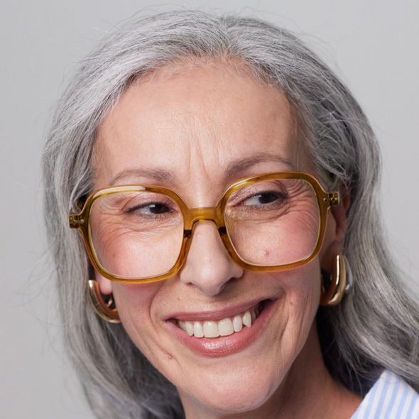 Woman wearing large golden green Izipizi glasses with a grey background