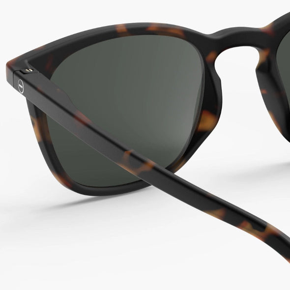 Sunglasses with tortoiseshell frame and dark lenses on a white background