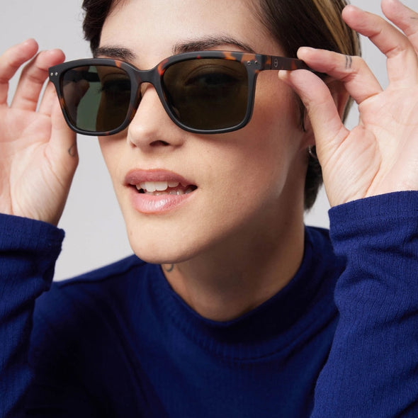 Person wearing dark sunglasses with a neutral background
