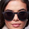 Close-up of a person wearing dark sunglasses with a neutral background