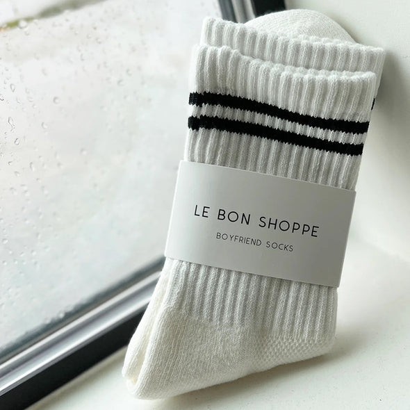 White socks with black stripes and 'Le Bon Shoppe' label on a light background