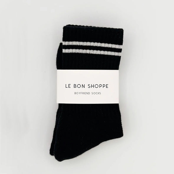 Black socks with white stripes and 'Le Bon Shoppe' label on a light gray background
