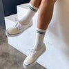 White sneakers with blue accents worn with white socks on a neutral background