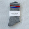 Gray socks with red and blue stripes on a gray background, featuring 'Le Bon Shoppe' label.