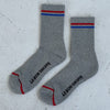 Gray socks with red and blue stripes and 'Le Bon Shoppe' branding on a light gray background