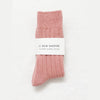 Rose Pink cashmere socks with a white label on a light grey background